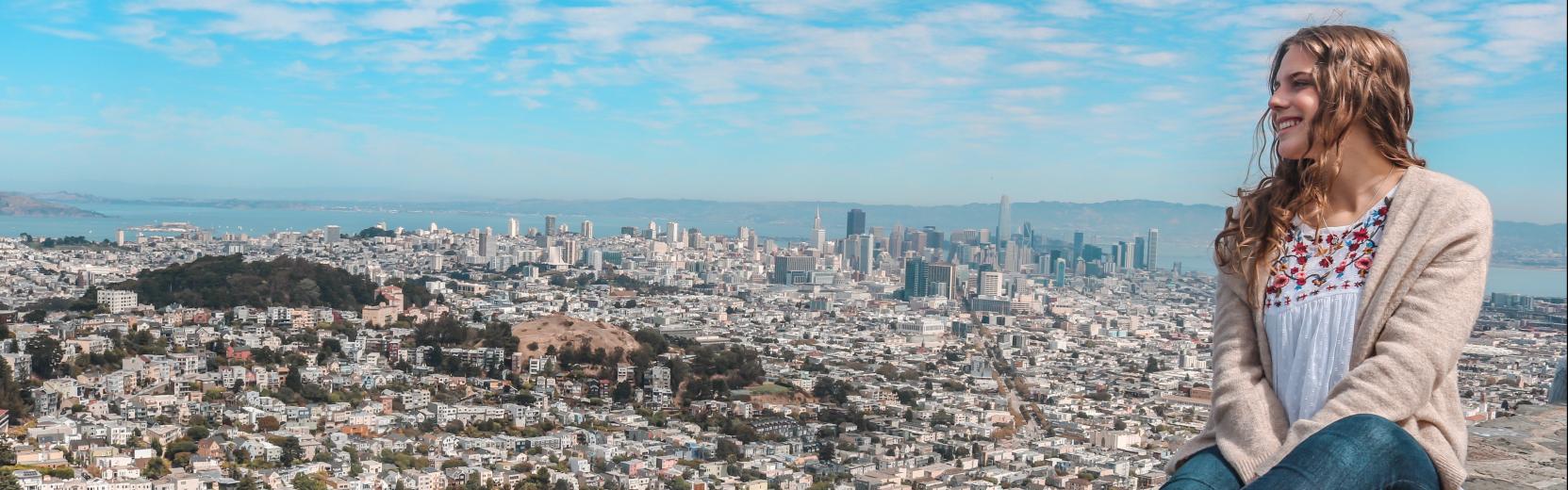 Au pair seduto su un muro che guarda la città